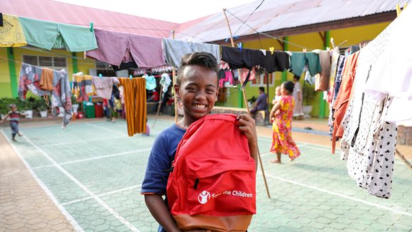 Equidad educativa - Un niño sonriente enseñando una mochila