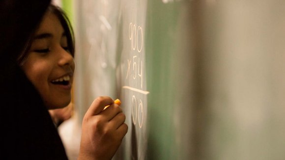 Niña en un colegio escribiendo en una pizarra