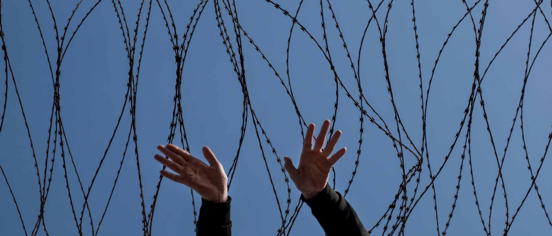 Sentencia devoluciones en caliente - Una valla con manos de un niño saliendo de ella Sentencia devoluciones en caliente