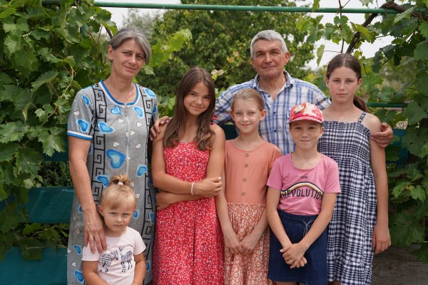 Stanislav, de 57 años, con su esposa Oksan*, Anastasiia(3), Mariia(14), Victoria(9), Larisa(9) y Olga(14) [de izquierda a derecha] posan para un retrato familiar en el jardín cercano a su casa en el sur de Dnipro, Ucrania.