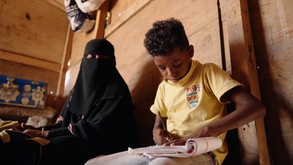 Khaled, de 12 años, estudia con su madre Saeeda en su casa en un campamento de Lahj, Yemen. Foto: Save the Children 